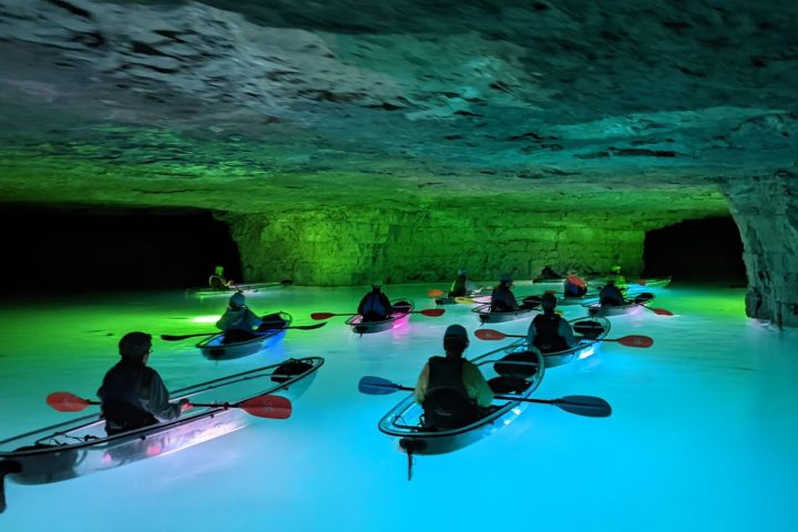A group of kayakers tour the Gorge Underground in Crystal Clear Kayaks surrounded by the colorful illumination of underwater LEDs.