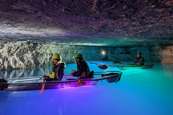 A tandem and single Crystal Clear kayak are shown at the Gorge Underground and each kayak is illuminated by colorful underwater LEDs.