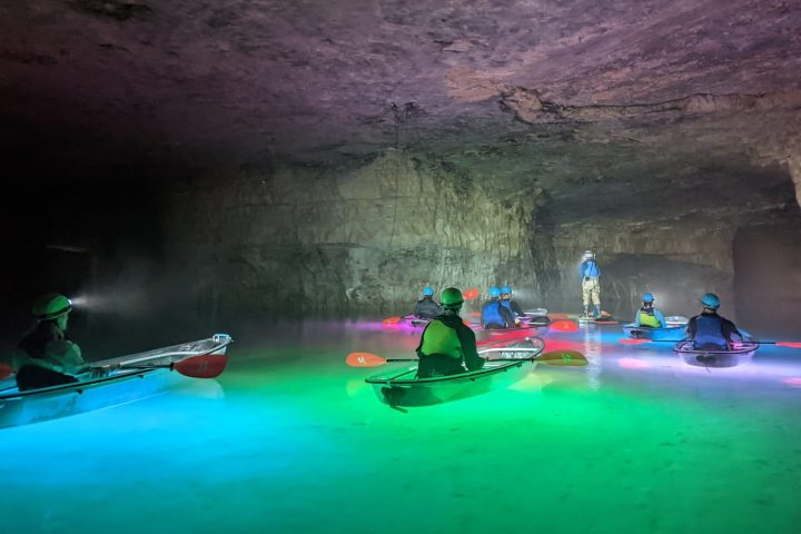 A group of kayakers tour the Gorge Underground in Crystal Clear Kayaks surrounded by the colorful illumination of underwater LEDs.